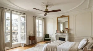 Ventilateur de plafond extra silencieux installé dans une chambre haussmannienne avec cheminée en marbre et balcon parisien