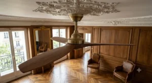 Gros plan sur un ventilateur de plafond aux pales en bois noble de noyer s'accordant avec le mobilier d'un appartement haussmannien
